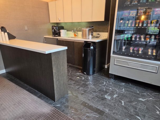 Kitchenette with vending machine Modern kitchenette with coffee maker, sink, and vending machine against a marble floor.