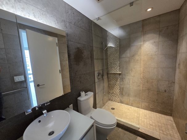 Nice shower Modern bathroom featuring a shower, toilet, sink, and stone wall tiles.