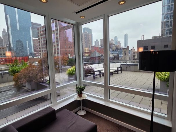Wrap Terrace View of a city skyline through large windows, with a rooftop terrace and greenery.