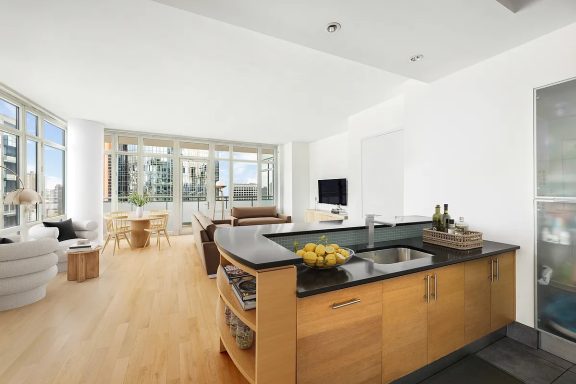 Living room Modern kitchen with wooden cabinets and a view of a bright living space.