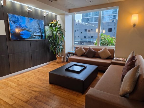 Lounge area with a TV Modern lounge area with a TV, coffee table, and large windows overlooking the city.