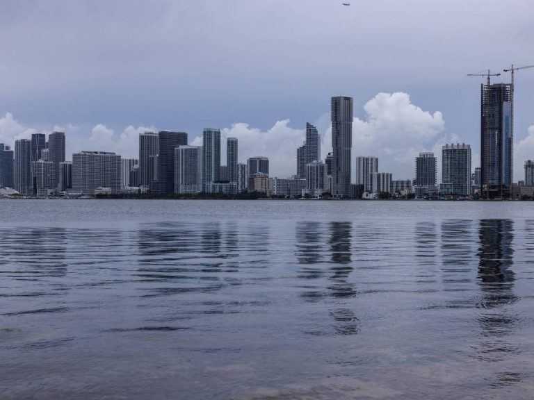 Manhattan skyline City skyline reflected in calm water under a cloudy sky.