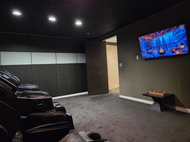 Massage chairs to relax Home theater room with reclining chairs and a TV on the wall.