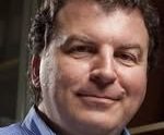 Appraisal Jonatthan Miller Smiling man with curly hair, wearing a blue collared shirt.