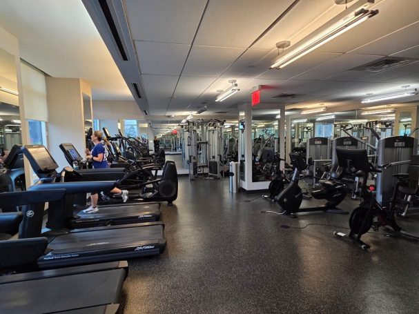 Gym A spacious gym with rows of exercise equipment and a few people working out.