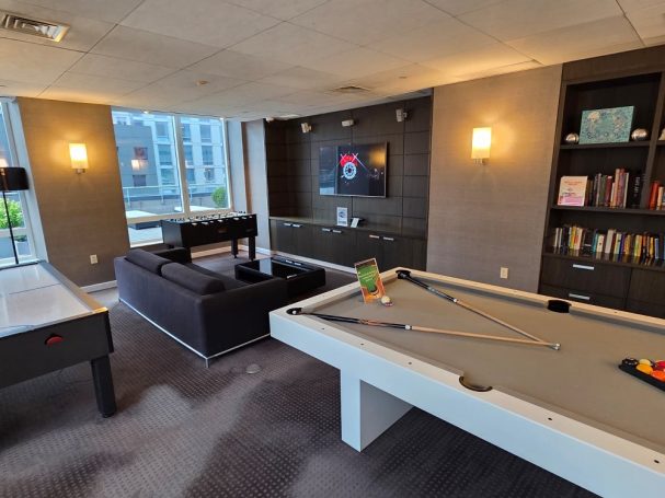 Game room Modern lounge area with a pool table, cozy seating, and a large window.