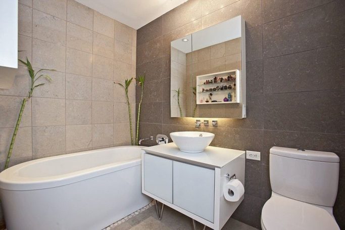 Master Bathroom Modern bathroom featuring a bathtub, sink, mirror, and a toilet with neutral-toned tiles.