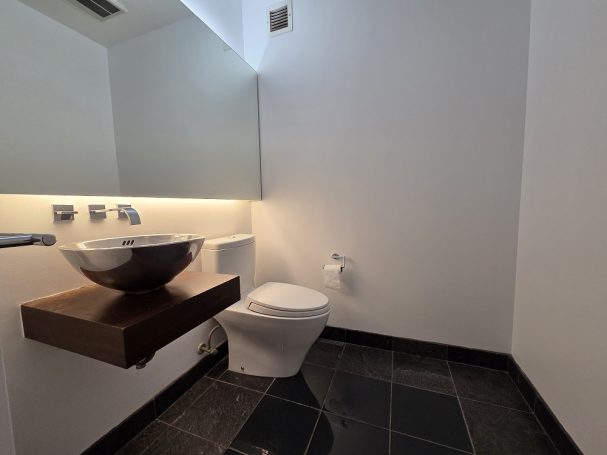 1/2 Bathroom Modern bathroom with a toilet, basin on a wooden shelf, and sleek black tiles.