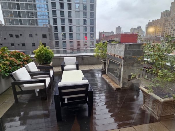 Fireplace Outside for the winter Rooftop terrace with seating, plants, and a fireplace, overlooking a city skyline.