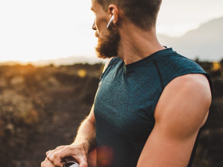 People vibe of East and West Man in a sleeveless shirt wearing earbuds, looking towards a sunset.