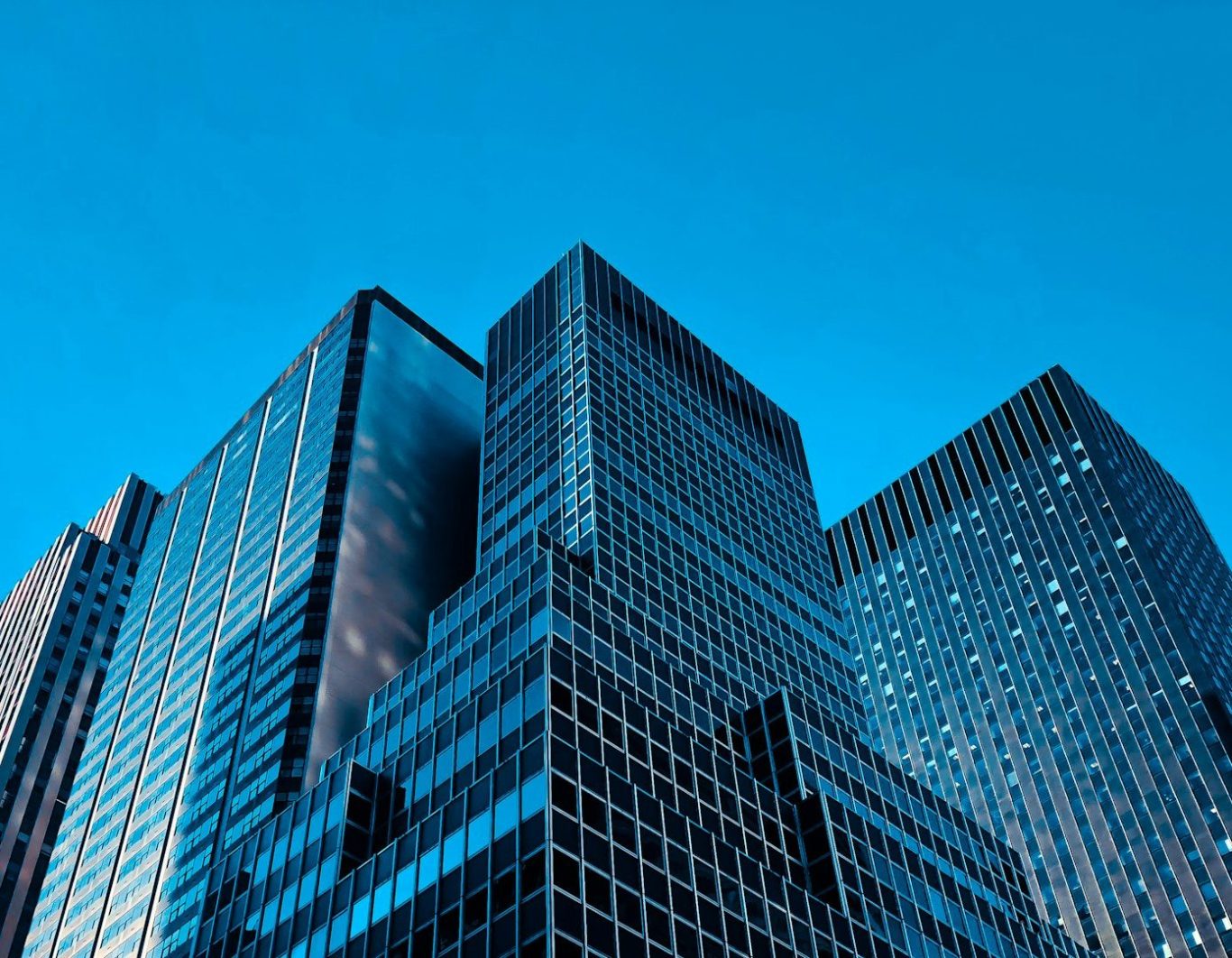 High-rises in NY for sale Modern skyscrapers with reflective glass facades against a clear blue sky.